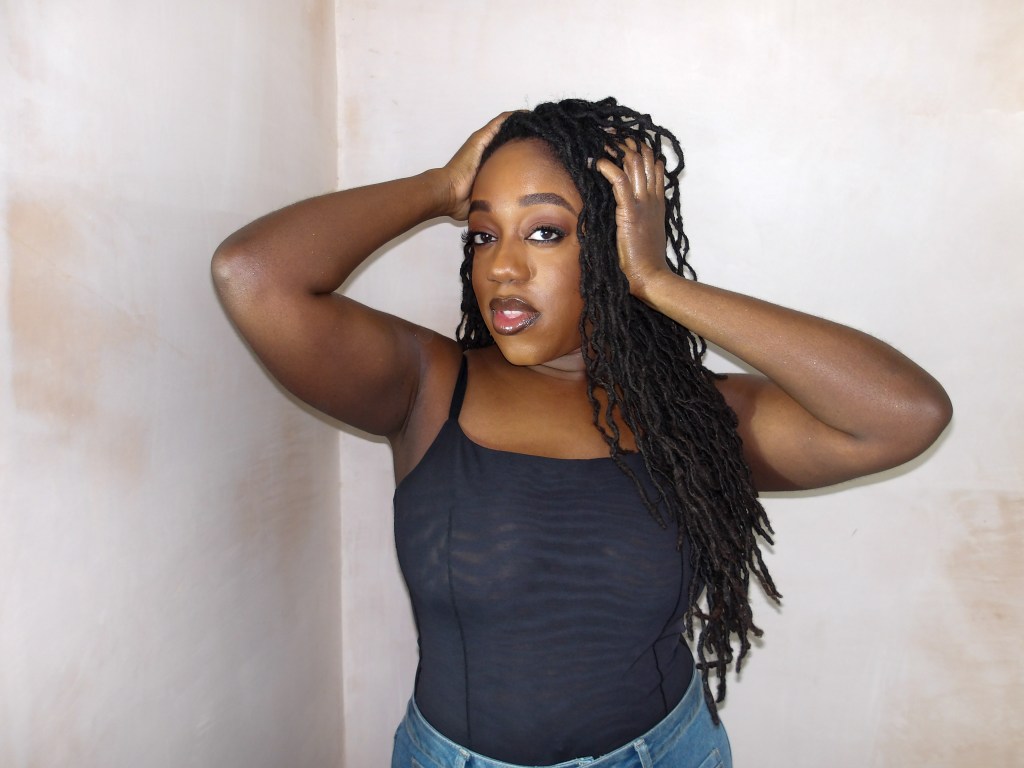 Close up photo of Naomi Sian who is a black lady with long curly locs