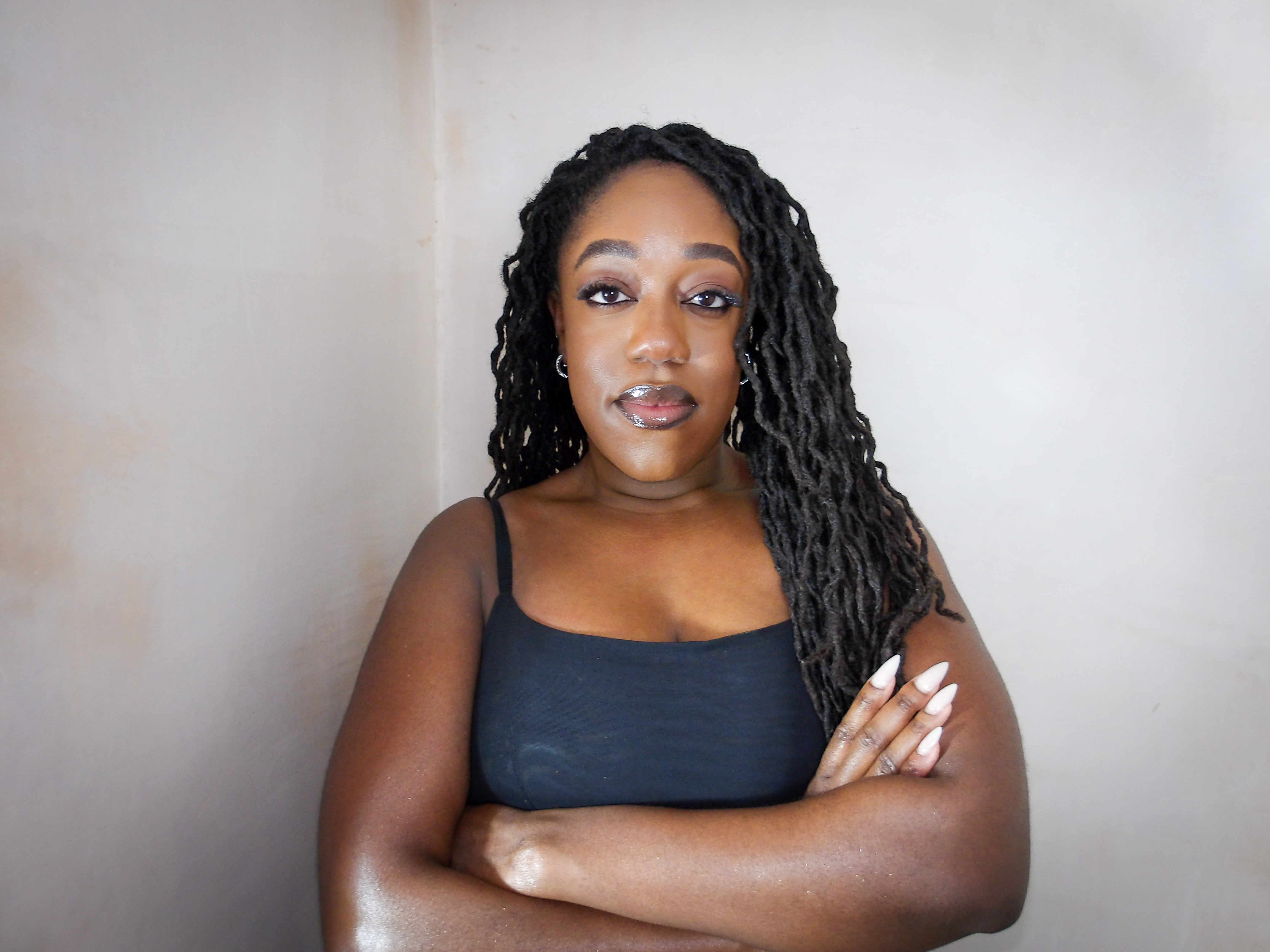 Close up photo of Naomi Sian who is a black lady with long curly locs.