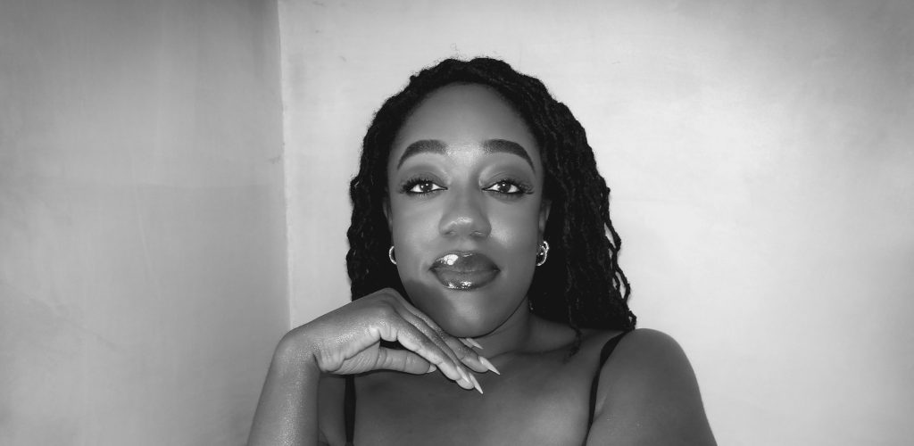 Close up photo of Naomi Sian who is a black lady with long curly locs