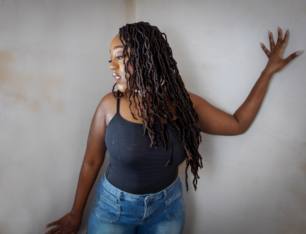 Close up photo of Naomi Sian who is a black lady with long curly locs