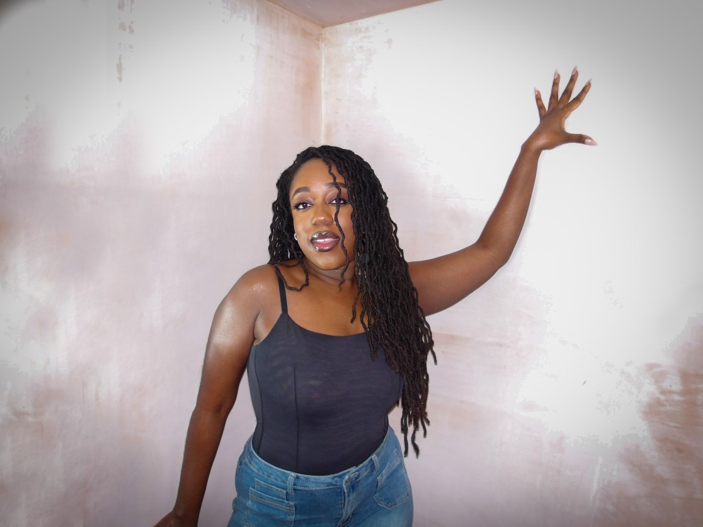 Close up photo of Naomi Sian who is a black lady with long curly locs