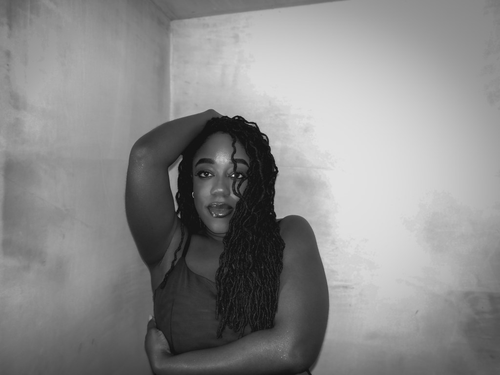 Close up photo of Naomi Sian who is a black lady with long curly locs