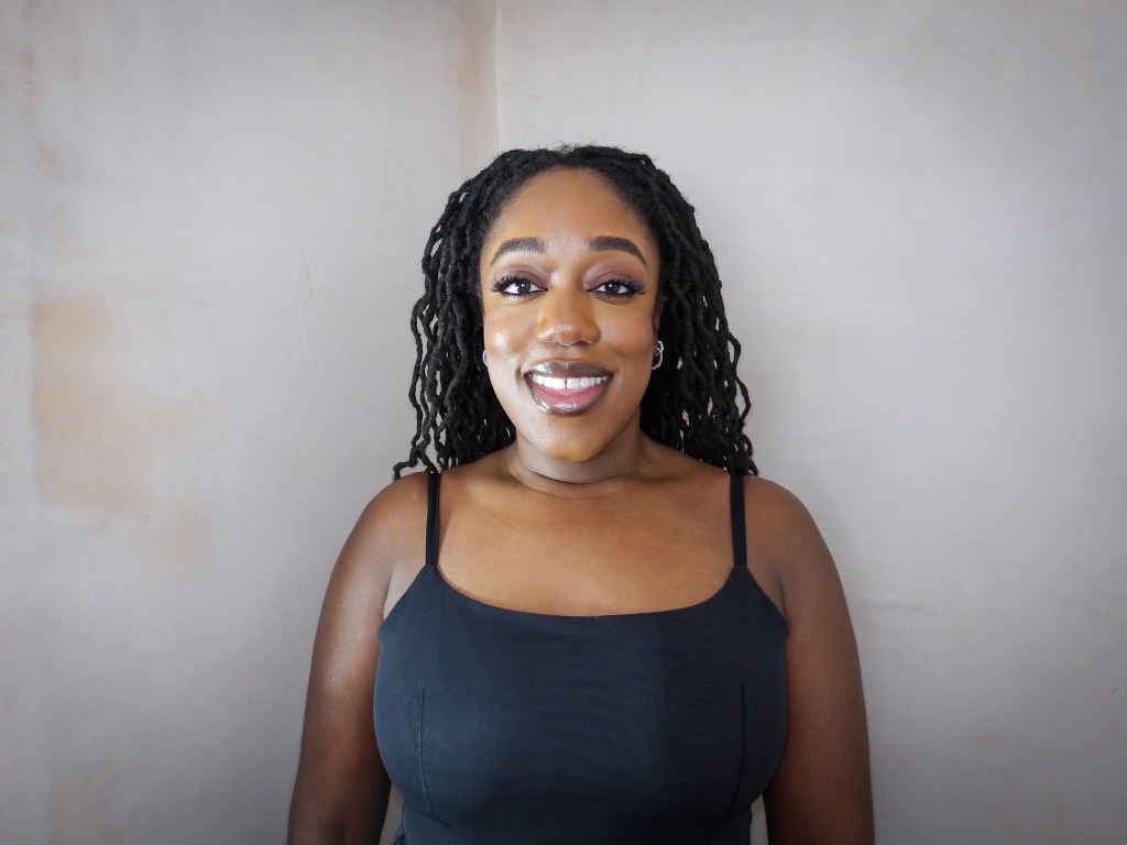 Close up photo of Naomi Sian who is a black lady with long curly locs