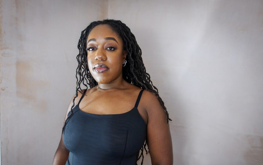 Close up photo of Naomi Sian who is a black lady with long curly locs